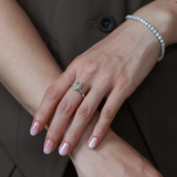 A model wearing the 3 ct oval ice-flower cut solitaire ring with an aesthetic, modern-heirloom stacking band against a textured backdrop.