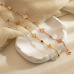 Three custom birth flower and stone bracelets in silver, 18K gold, and rose gold beautifully displayed on a white ceramic dish.