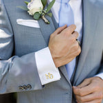 Gray suit with white shirt and gold cufflinks, close-up of hand adjusting jacket.