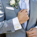 Gray suit with white shirt and gold cufflinks, close-up of hand adjusting jacket.