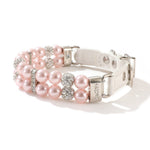 A pink pearl and rhinestone pet collar coiled with a matching pink leash.
