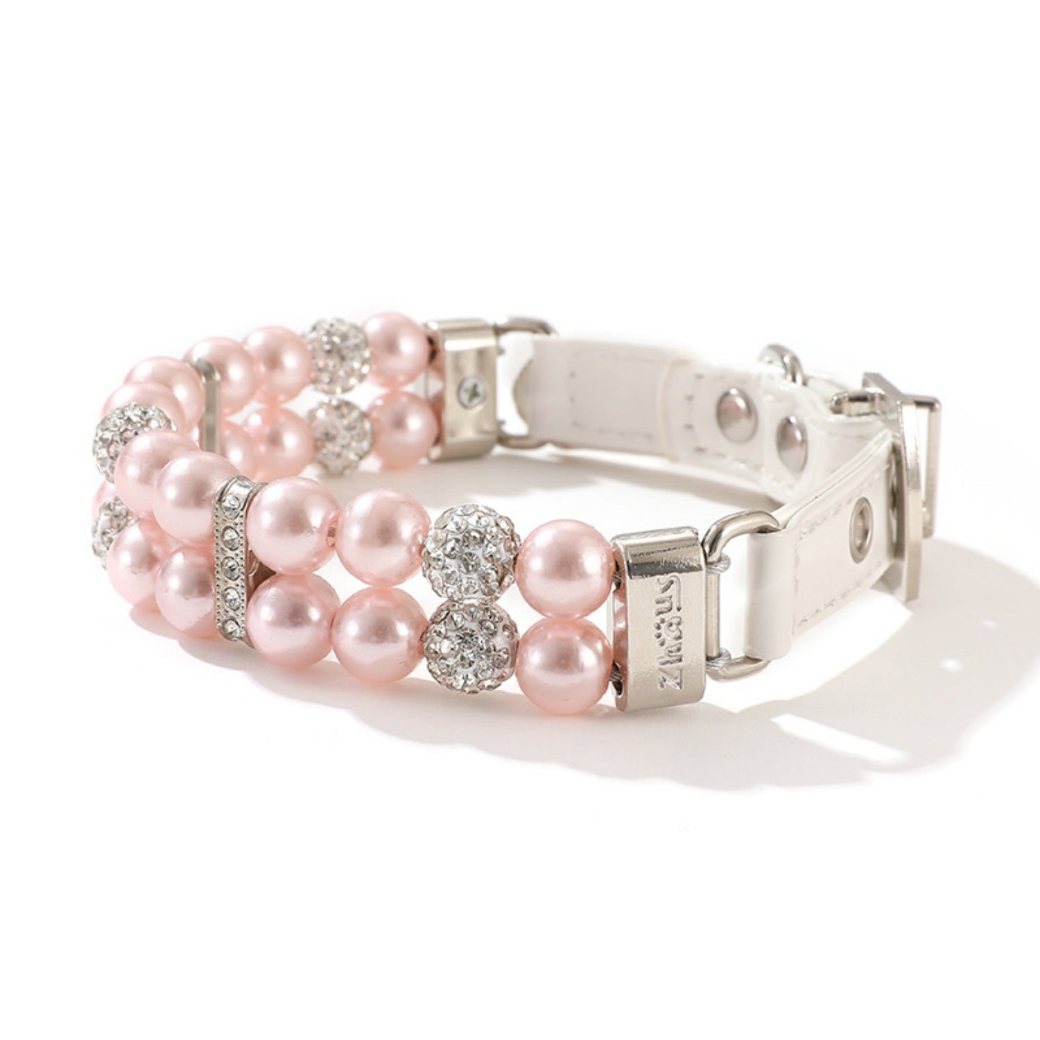 A pink pearl and rhinestone pet collar coiled with a matching pink leash.