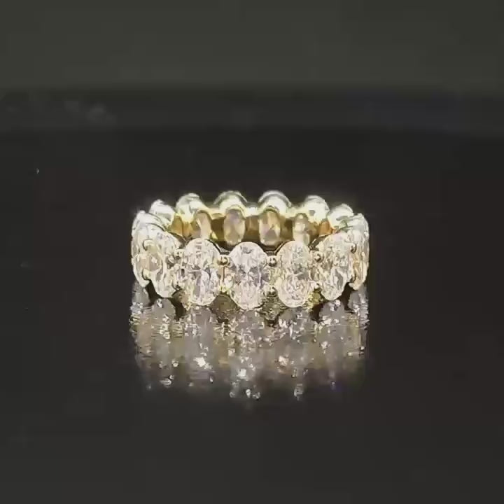 A dynamic video of the full oval diamond eternity band rotating on a dark reflective surface, capturing the brilliant fire of the VS clarity stones.