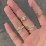Three variations of the Shooting Star Spark ring (Oval, Round, and Cushion cuts) held in a hand to show the celestial design options.