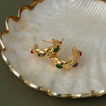 Retro-inspired quilted gold gemstone earrings resting on a white seashell for a luxury aesthetic.