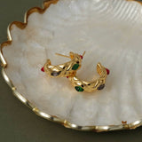Retro-inspired quilted gold gemstone earrings resting on a white seashell for a luxury aesthetic.