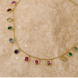 Close-up flat lay of the rainbow station necklace, highlighting the vibrant purple, blue, green, yellow, and pink CZ stones.