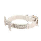 Side view of a white pet collar showing a metal buckle, sizing holes, and bands of clear rhinestones leading to a bow tie.