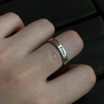 A silver "I'm fine" ring worn on a finger, with the hidden inside engraving leaving a faint, symbolic "save me" imprint on the skin.