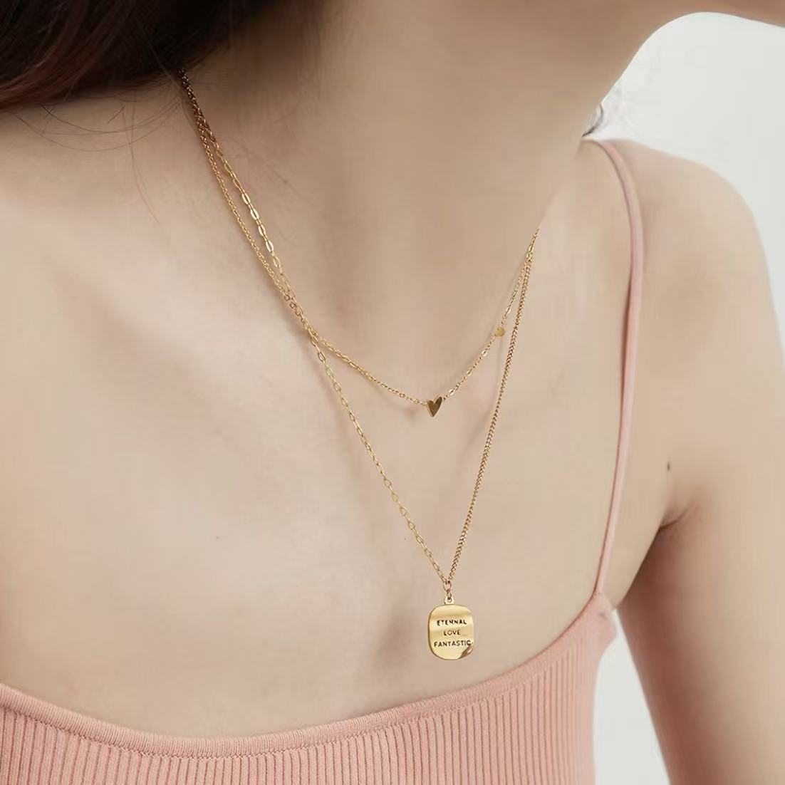 Close-up of a woman wearing the dainty 18K gold plated scattered hearts station necklace on her collarbone.