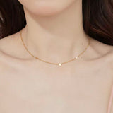 Close-up of a woman wearing the dainty 18K gold plated scattered hearts station necklace on her collarbone.