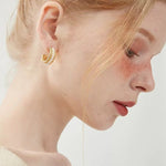 Side profile of a model highlighting the textured, vintage design of a chunky gold braided pearl hoop earring.