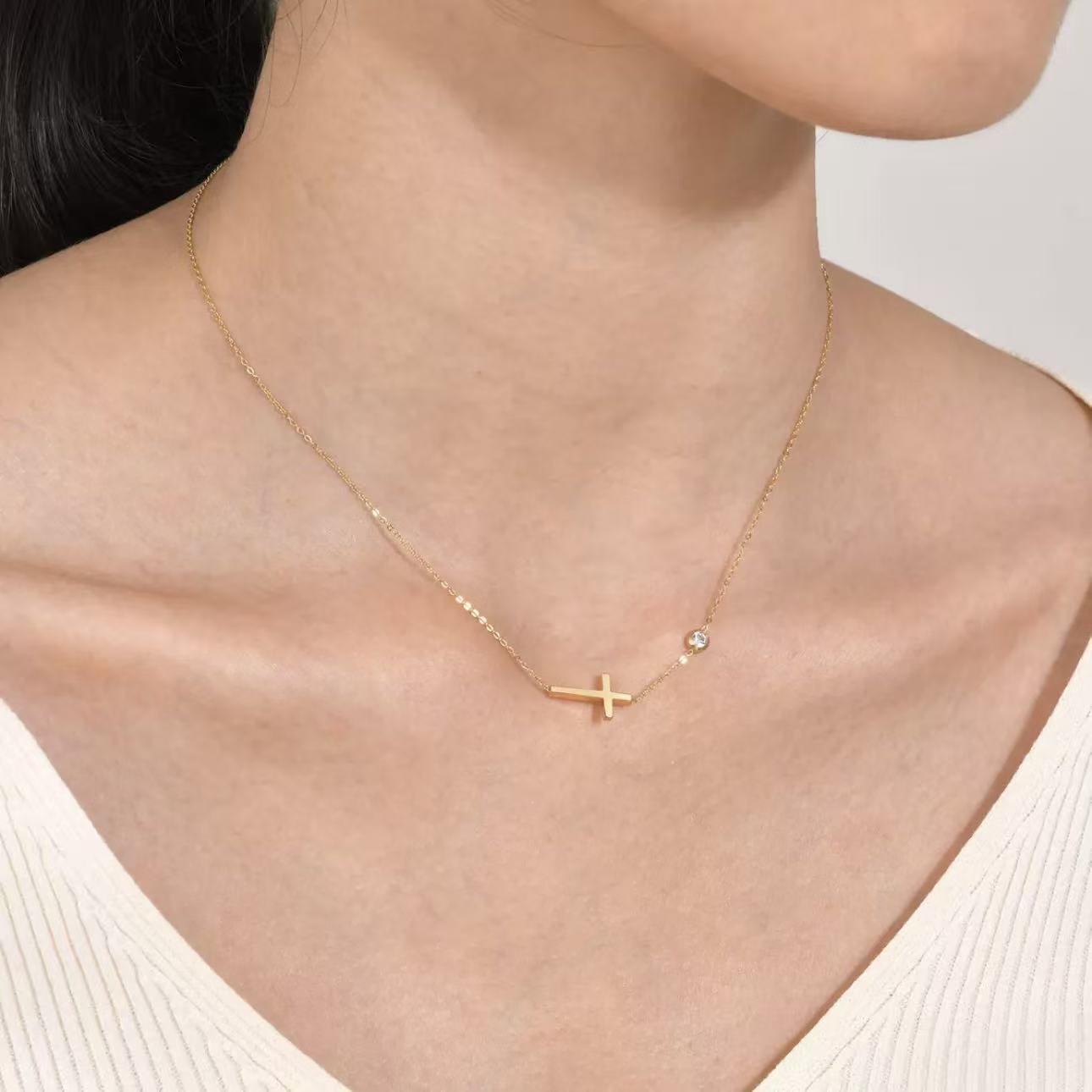 A model wearing the minimalist 18K gold plated sideways cross necklace with a blazer, showcasing its modern elegance.