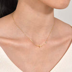 A model wearing the minimalist 18K gold plated sideways cross necklace with a blazer, showcasing its modern elegance.