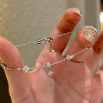 A hand holding a 925 sterling silver clover bracelet, demonstrating the innovative adjustable sliding bolo clasp for a perfect fit.
