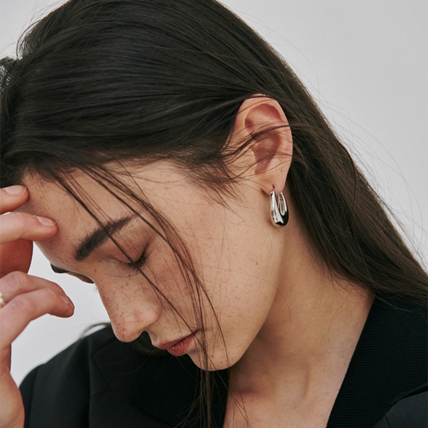 Side view of a model wearing the polished S925 sterling silver U-shape hoop earrings.