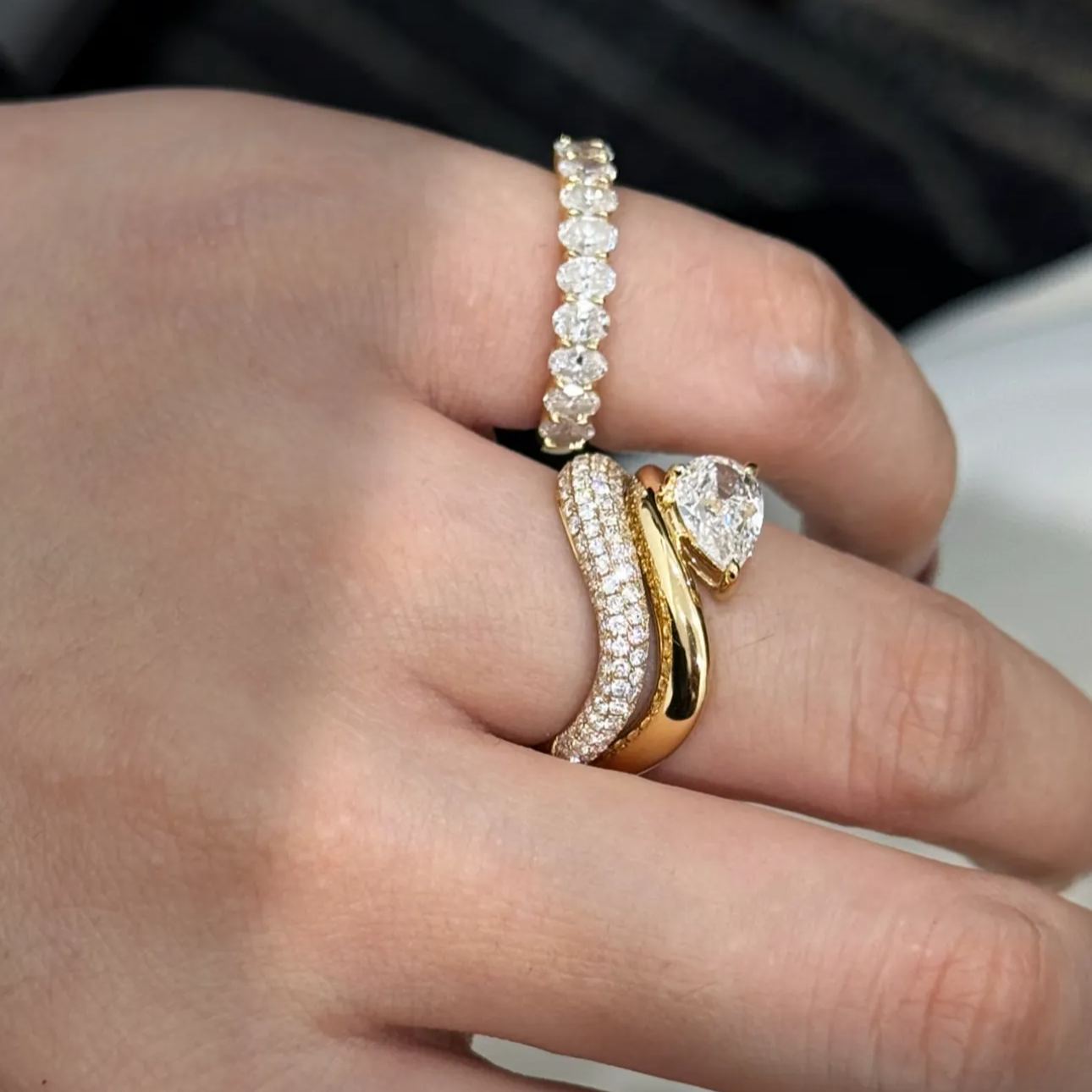 A woman's hand showcasing the Oval Eternity Band beautifully stacked with an engagement ring for a luxurious bridal look.