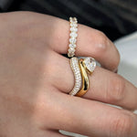A woman's hand showcasing the Oval Eternity Band beautifully stacked with an engagement ring for a luxurious bridal look.