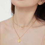 The delicate gold scattered hearts necklace draped over fingers to show the precise scale of the tiny heart charms.