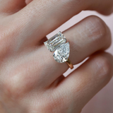A 3.70 ctw Toi et Moi ring featuring a brilliant emerald-cut and pear-cut lab diamond on a model's finger in 18K gold.