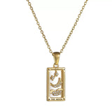 A gold rectangular tarot card pendant labeled THE MOON, featuring a white enamel background, a gold crescent moon, clouds, and star motifs accented with clear cubic zirconia.