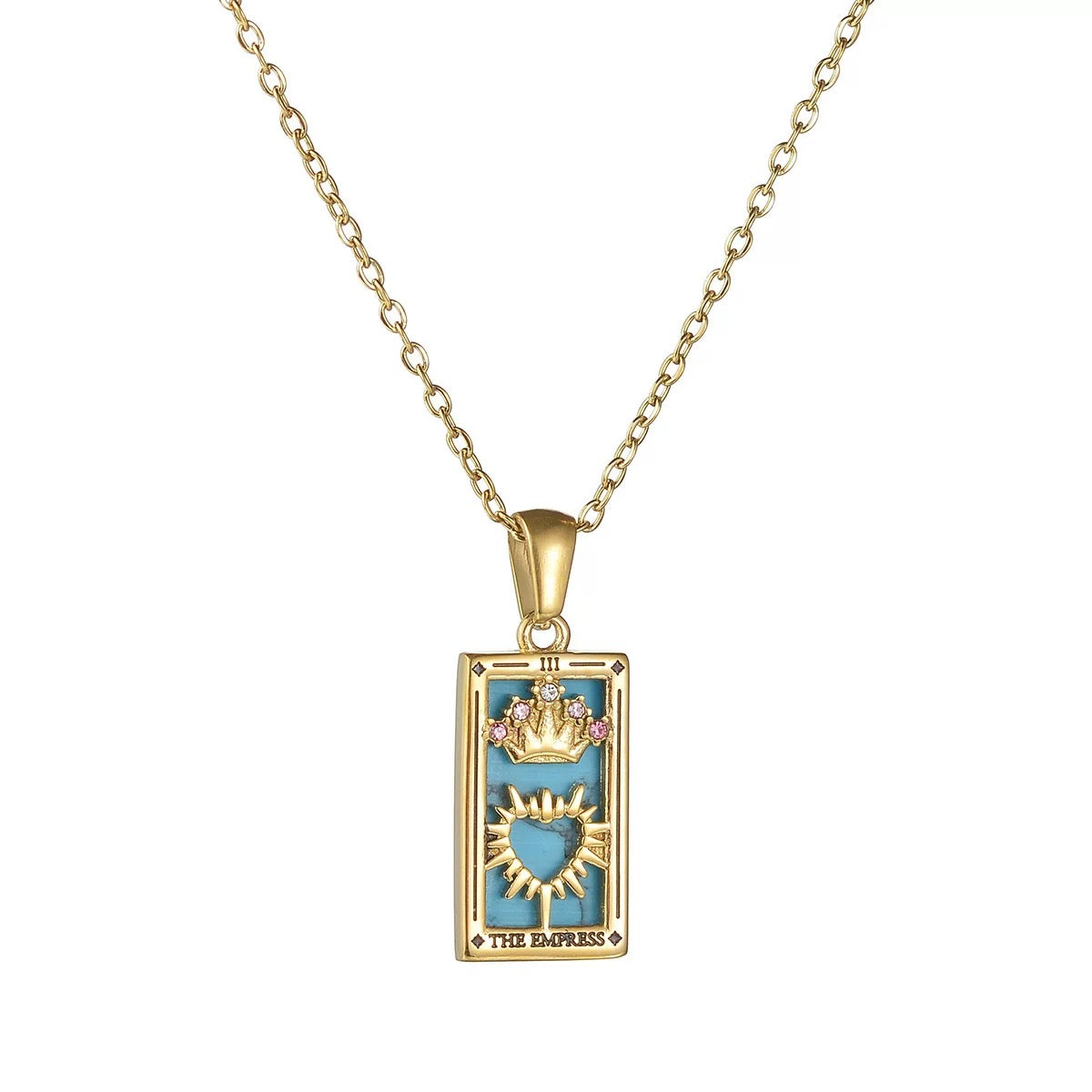 Close-up of an 18K gold plated tarot card pendant labeled THE EMPRESS, showcasing its turquoise enamel background, pink-jeweled crown, and sunburst heart design.